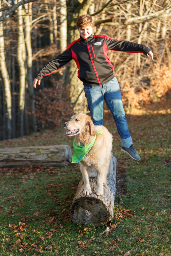 Hund Timber und Kind balancieren auf einem Baumstamm